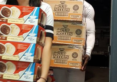 Volunteers carry bulk pudding and cup of noodle soups for unpacking and distribution in Kidz Power Pacs, free food for hungry school aged children